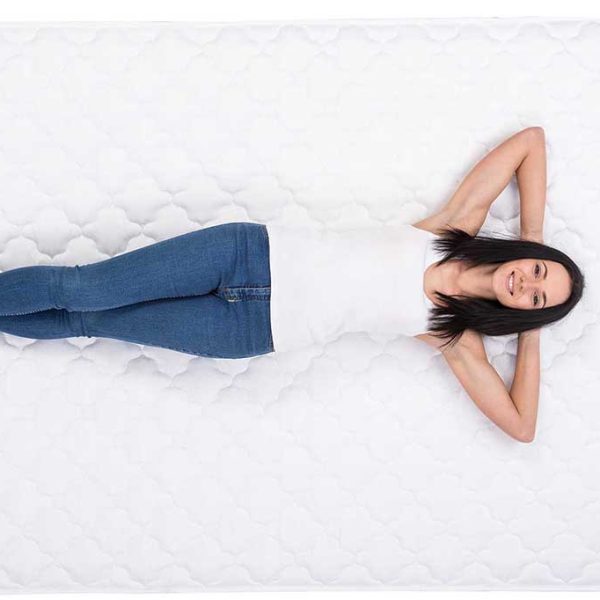 Young woman is lying on the white bed.