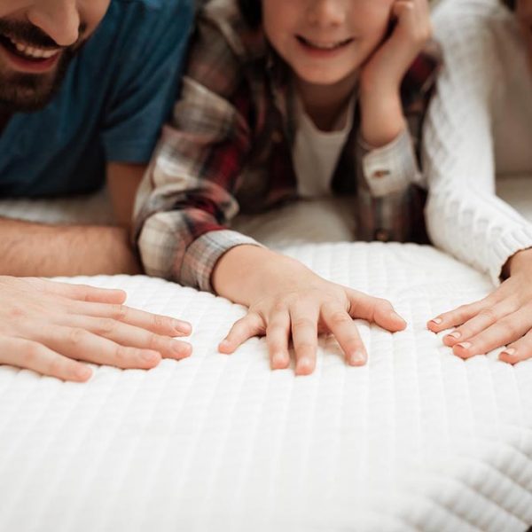 Closeup Happy Family Touching Mattress in Store